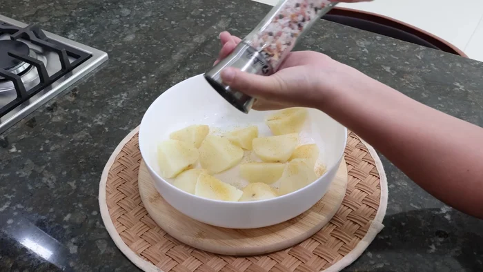 Agregar las papas cocidas a un recipiente, sazonar con ajo en polvo, sal y pimienta. Machacar con un tenedor.