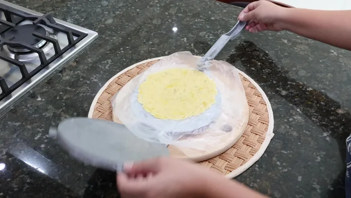 Aplastar la masa hasta obtener una tortilla delgada.