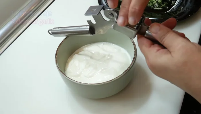 Machacar un diente de ajo (o rallarlo o cortarlo en trocitos pequeños) y añadirlo al yogur.