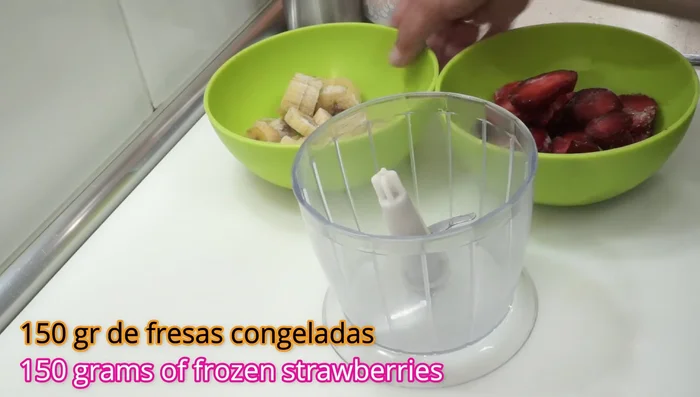 Para el segundo helado, utilizar 150g de fresas congeladas y un plátano congelado. Picar un poco las fresas antes de triturar para facilitar el proceso.