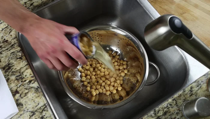 Escurrir y enjuagar dos latas de garbanzos.