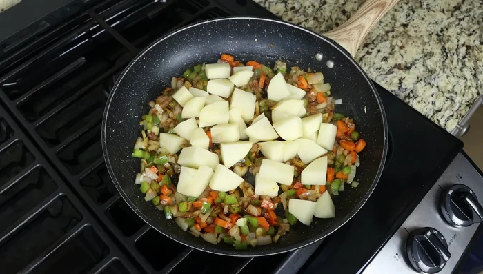 Agregar la patata y los garbanzos a la sartén. Mezclar bien.