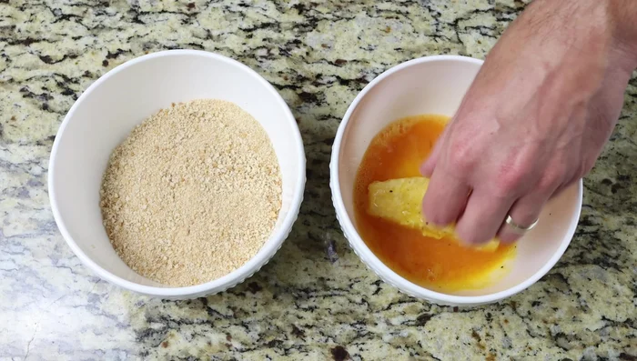 Rebozar los palitos de pescado: primero en el huevo batido, luego en el pan rallado.