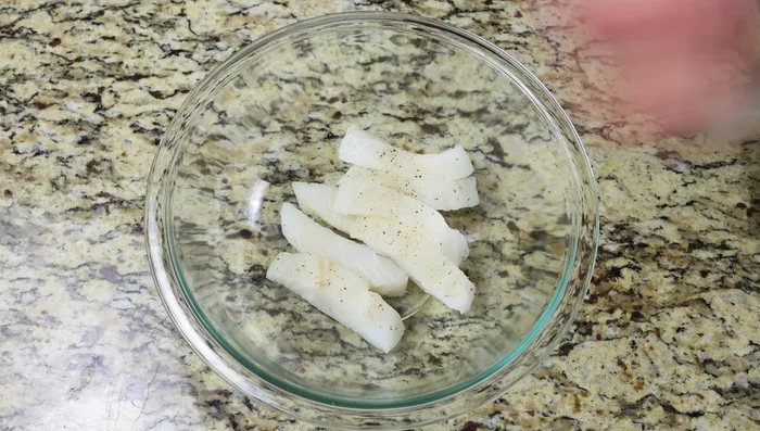 En un tazón, mezclar los palitos de pescado con la harina hasta cubrirlos uniformemente.