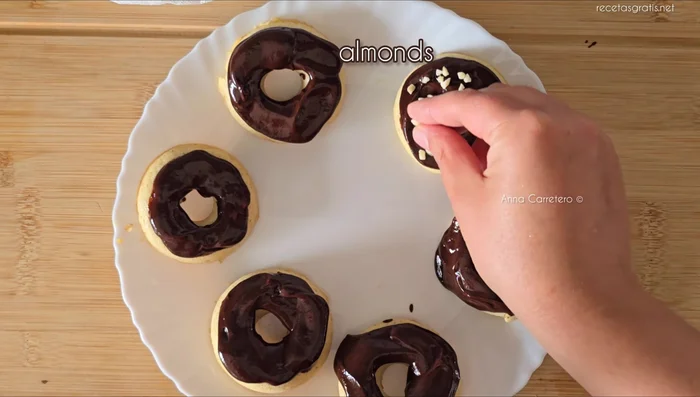 Cubrir las donas con el chocolate derretido y crocanti de almendra.